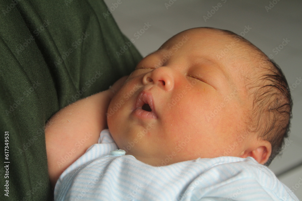 Portrait of a newborn boy who sleeps sweetly and smiles in he sleep in red clothes at a photo shoot of newborns
Portrait of a newborn boy who sleeps sweetly and smiles in he sleep in red clothes at a photo shoot of newborns