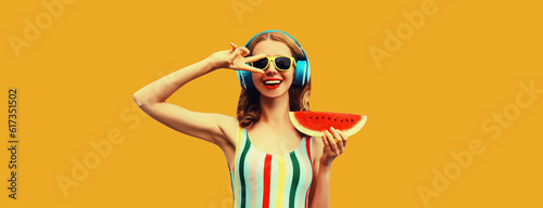 Summer colorful portrait of cheerful happy laughing young woman 20s in headphones listening to music with juicy slice of watermelon on yellow background