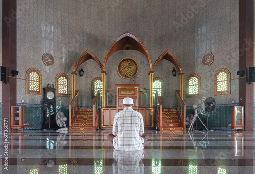 Religious muslim man sits and recite prayers for God on the floor in the Al Alawi Mosque. He prays for God in the mosque, The religion of islam, Muslim mosque, Space for text, Selective focus. photo