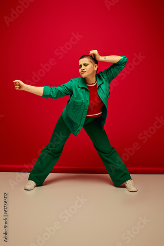 fashion choices, modern backdrop, emotional and young woman in stylish attire posing on red background, full length, generation z, youth culture, personal style, curvy fashion