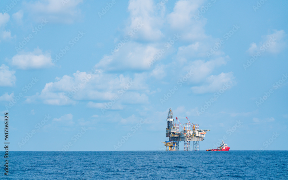 Offshore oil rigs in the Gulf and large supply ships nearby in sunny weather.