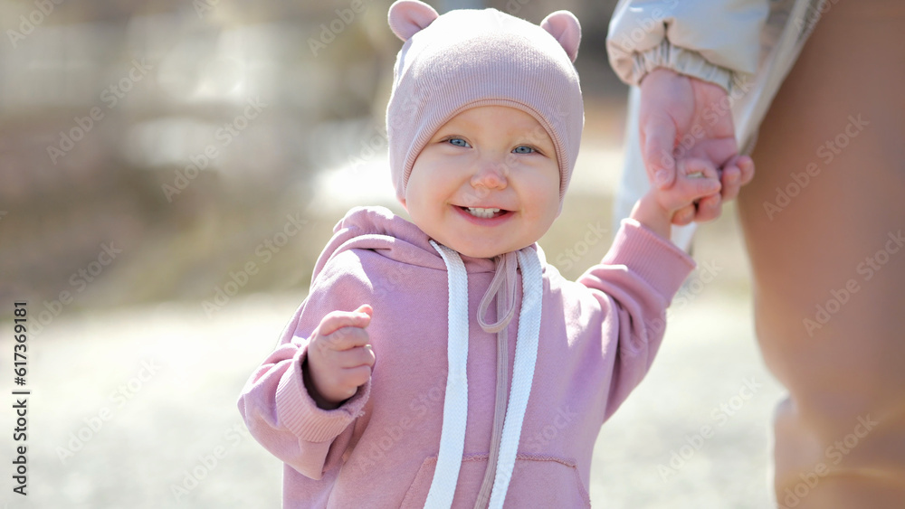 © lenblr - Excited toddler enjoys walking and holding mother hand at resort. Toddler girl with amused expression smiles and laugh during walking