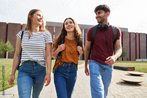 Group of three caucasian students walking through university campus