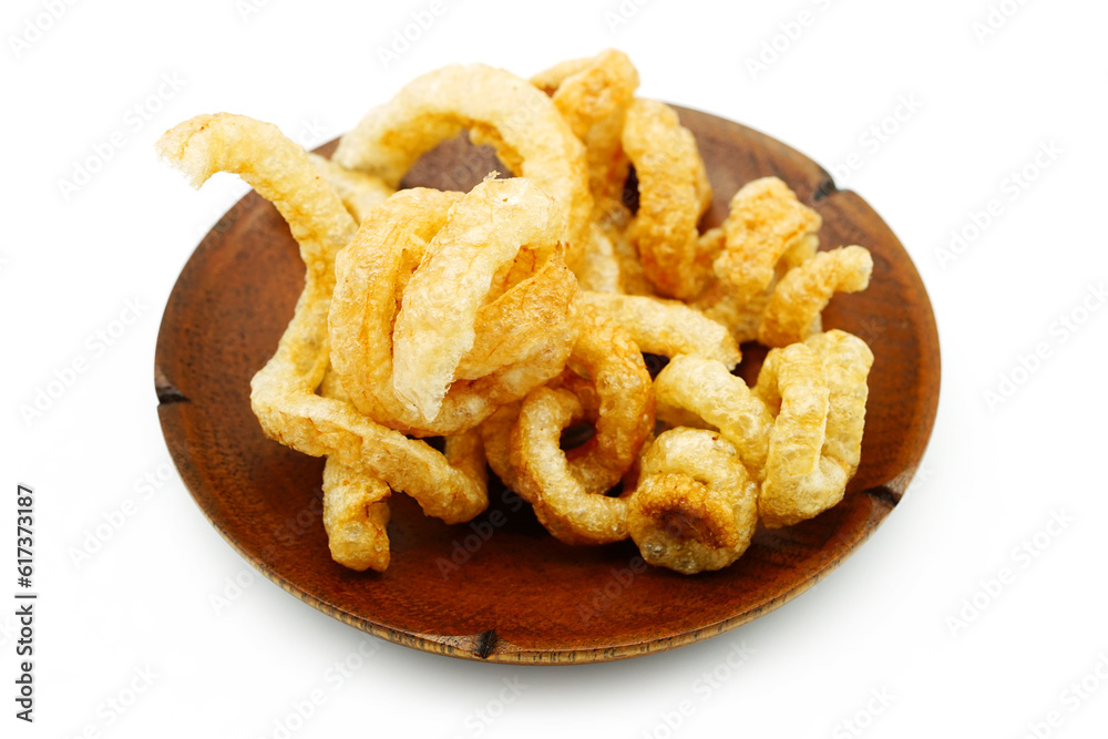 Pork snack or Pork scratching leather lean pork fried crispy and blistered in wood plate isoloated on white background. Pork snack or Pork scratching leather lean pork fried crispy and blistered in wood plate isoloated on white background.