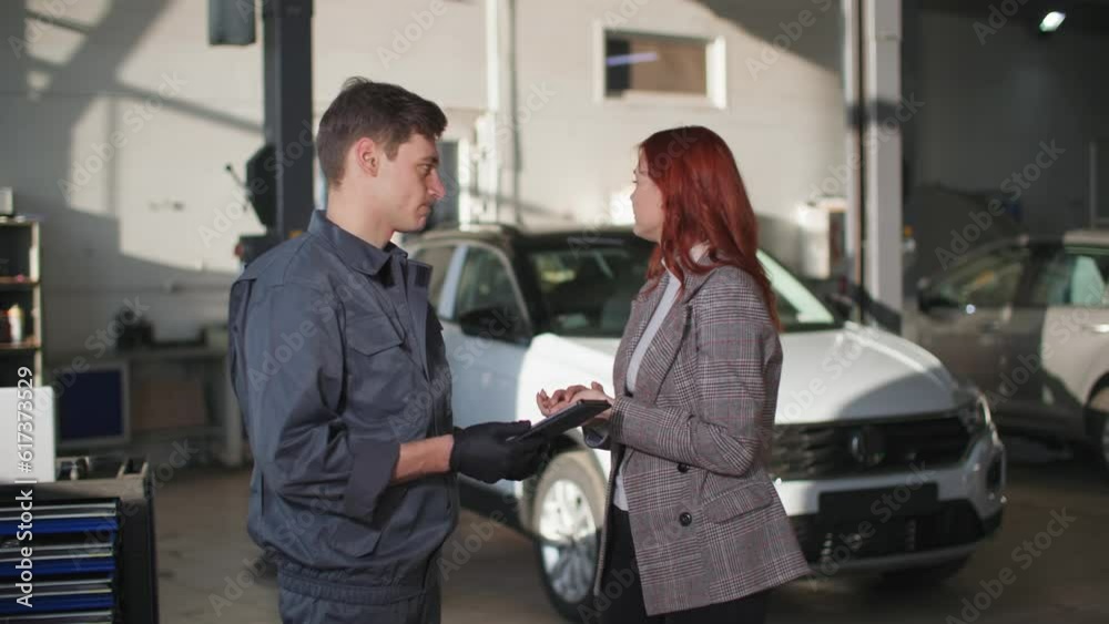 maintenance of a vehicle, a male mechanic with a tablet in his hands explains to frustrated woman owner of car about an engine breakdown at a technical station maintenance of a vehicle, a male mechanic with a tablet in his hands explains to frustrated woman owner of car about an engine breakdown at a technical station