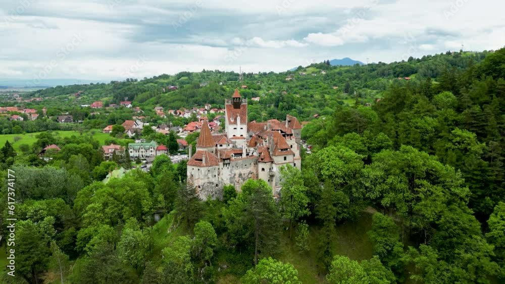 Medieval Bran Castle - Romania, aerial drone perspective. Drone going backwords. In background is the village of Bran. Known as Dracula's Castle, it is visited annually by many foreign tourists. Medieval Bran Castle - Romania, aerial drone perspective. Drone going backwords. In background is the village of Bran. Known as Dracula's Castle, it is visited annually by many foreign tourists.