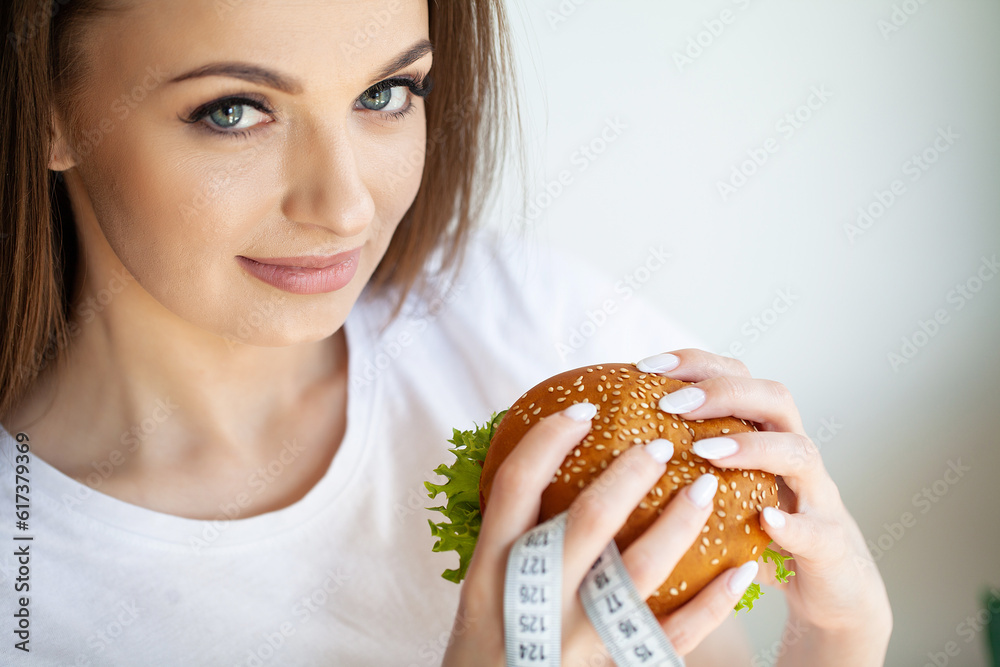 Young woman eats a fatty burger, weight loss concept Young woman eats a fatty burger, weight loss concept