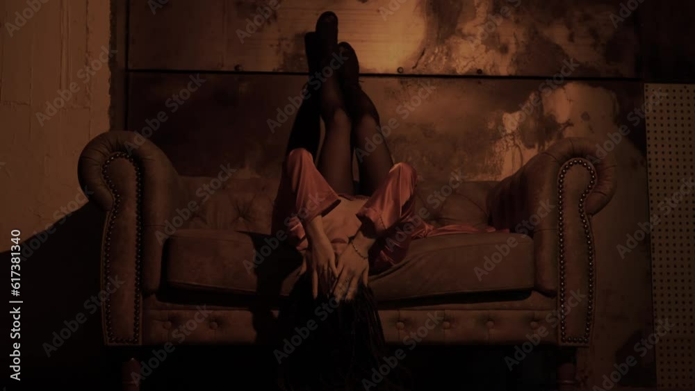 Attractive beautiful sexy Asian woman lies on the sofa upside down and flirts, touches the body, poses in a dress in a dark room Attractive beautiful sexy Asian woman lies on the sofa upside down and flirts, touches the body, poses in a dress in a dark room