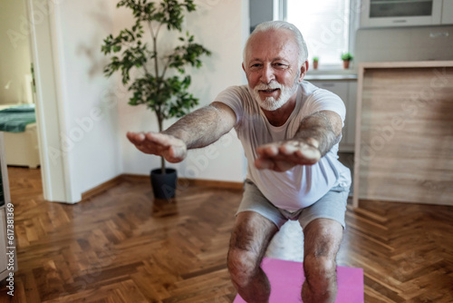 Fit senior man exercising at home doing lunges exercise. Mature man stretching at home.