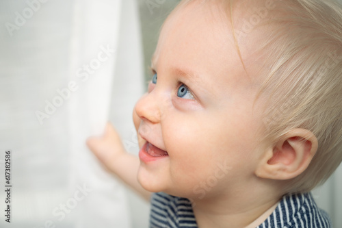 Cute baby with blue eyes - closeup portrait. Little boy at home looking away.