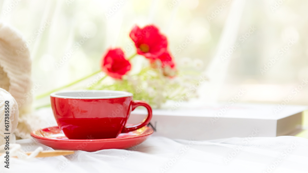 Coffee morning. Red steaming cup of hot coffee for relax after working hobbies crochet on white wooden near window with flowers on autumn and winter season. Lifestyle Concept Coffee morning. Red steaming cup of hot coffee for relax after working hobbies crochet on white wooden near window with flowers on autumn and winter season. Lifestyle Concept
