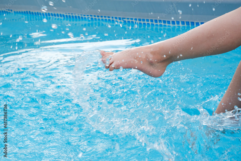 Kids legs splashing in water near swimming pool outdoors. Summertime activities for children. Copy space, closeup. Clear water