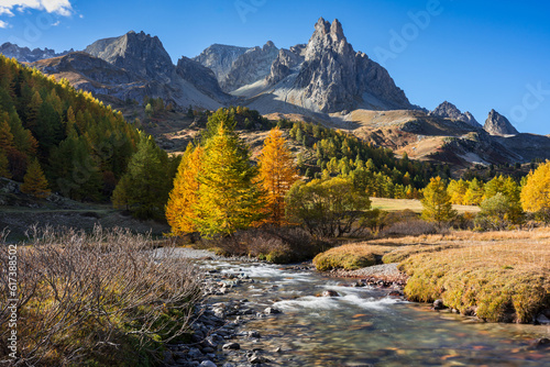 Claree Valley in the French Alps with larch trees and Main de Crepin mountain peak. Autumn in Cerces Massif. Hautes Alpes, France