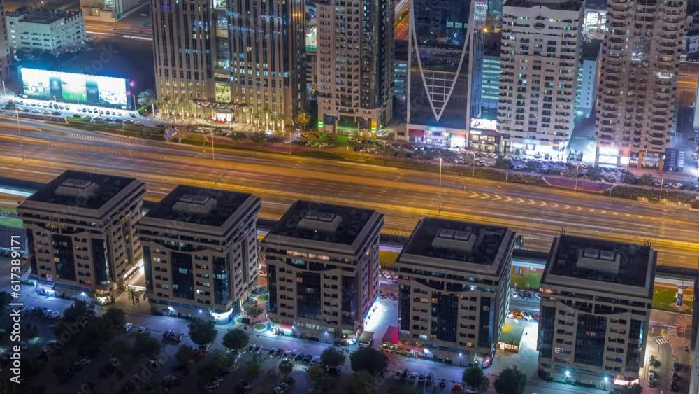 Buildings on Sheikh Zayed Road in Dubai aerial night timelapse, UAE. Skyscrapers in international financial district from above. Traffic on a highway and parking lot Buildings on Sheikh Zayed Road in Dubai aerial night timelapse, UAE. Skyscrapers in international financial district from above. Traffic on a highway and parking lot