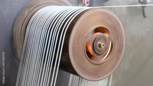 Fototapeta na wymiar Séchage de lanières industrielles sur un rouleau chauffant qui tourne à grande vitesse pour lisser et étirer les fibres.
