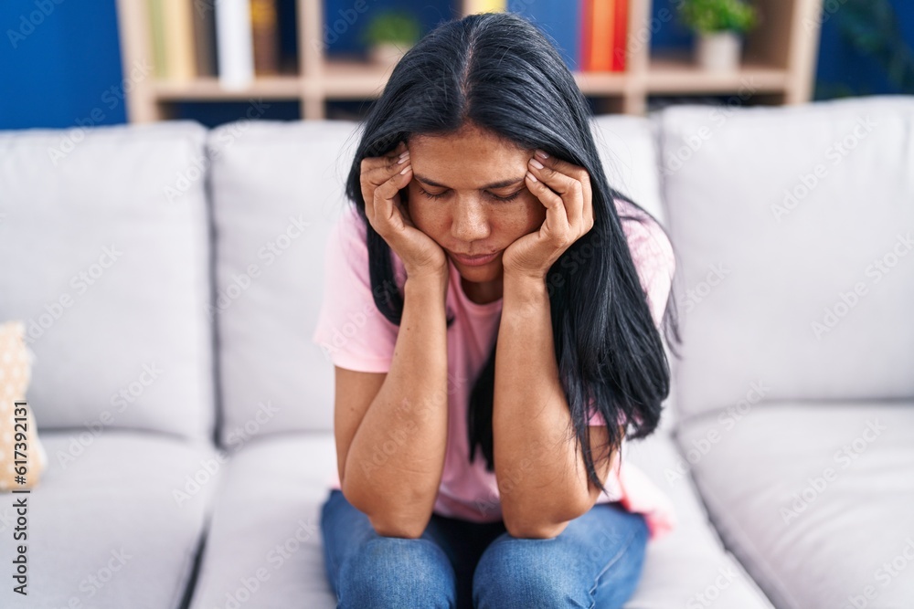 Middle age hispanic woman stressed sitting on sofa at home Middle age hispanic woman stressed sitting on sofa at home