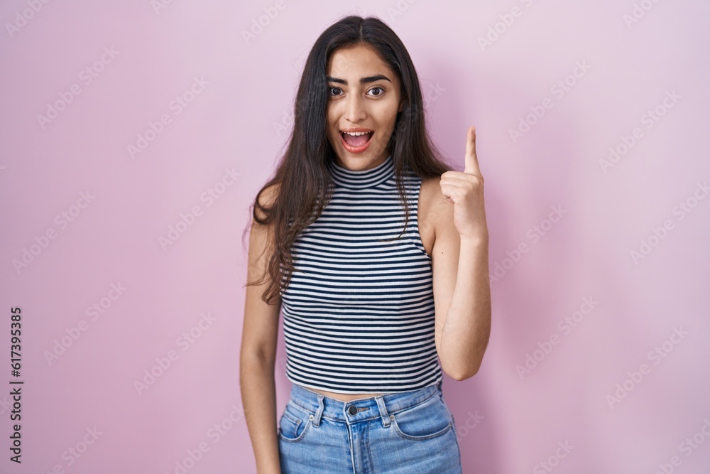 Young teenager girl wearing casual striped t shirt pointing finger up with successful idea. exited and happy. number one. Young teenager girl wearing casual striped t shirt pointing finger up with successful idea. exited and happy. number one.