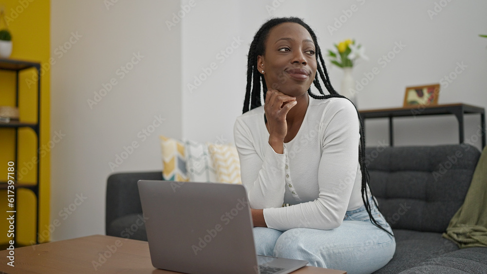 African american woman using laptop sitting on sofa at home African american woman using laptop sitting on sofa at home