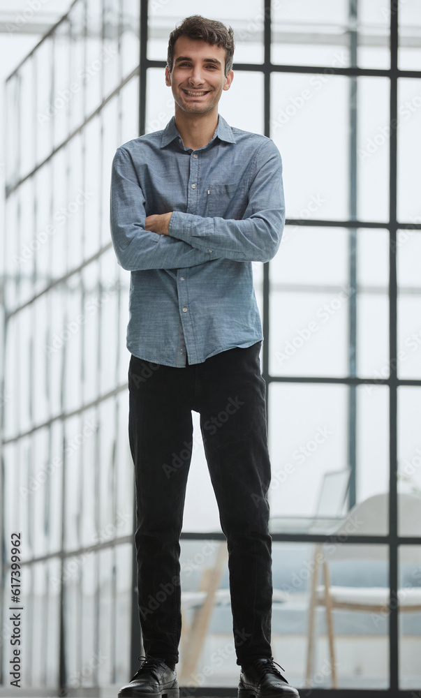 Full length portrait of handsome young businessman posing at camera with arms crossed