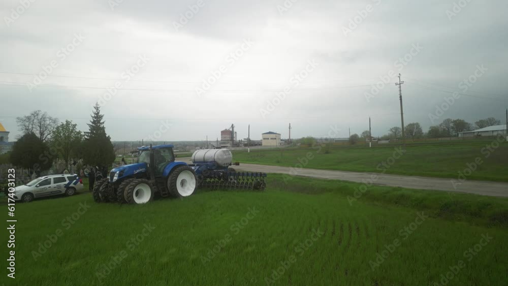 Blue tractor working on the wheat field doing liquid fertilizer injection Blue tractor working on the wheat field doing liquid fertilizer injection