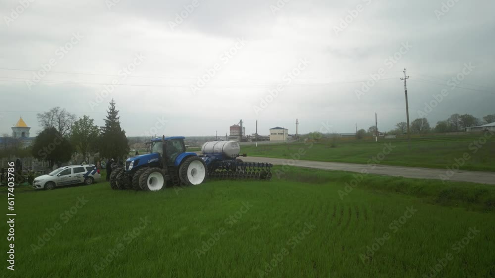 Blue tractor working on the wheat field doing liquid fertilizer injection Blue tractor working on the wheat field doing liquid fertilizer injection