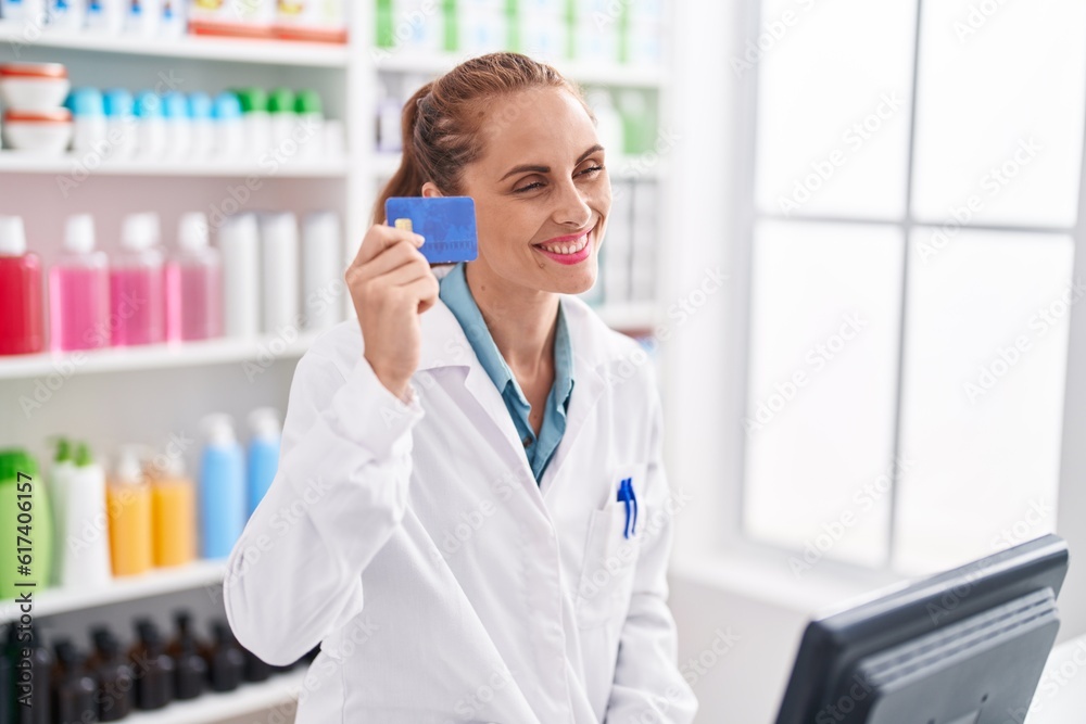 Young beautiful hispanic woman pharmacist smiling confident holding credit card at pharmacy