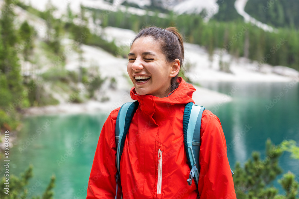 Portrait of delightful hiker woman with beautiful smile, mountains and lake around
