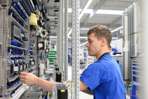 young operator assembles machine in a modern high tech factory - production of switch cabinets for industrial plant photo