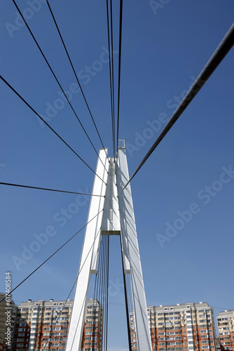 Modern urban cable-stayed bridge with metal ropes in the city district over clear cloudless blue sky