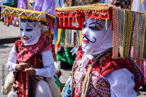 Cusco, a cultural fiesta, people dressed in traditional colourful costumes with masks and hats, brightly coloured streamers.