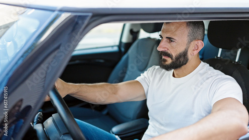 Young hispanic man driving car at street