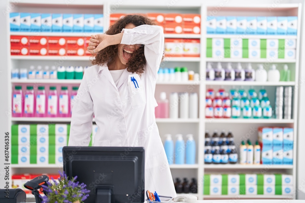 Hispanic woman with curly hair working at pharmacy drugstore smiling cheerful playing peek a boo with hands showing face. surprised and exited Hispanic woman with curly hair working at pharmacy drugstore smiling cheerful playing peek a boo with hands showing face. surprised and exited