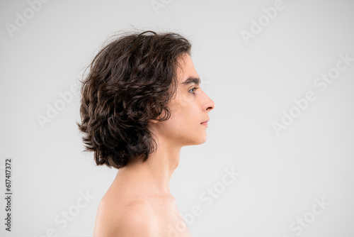 Profile of a handsome young man with lush curly hair on a white background