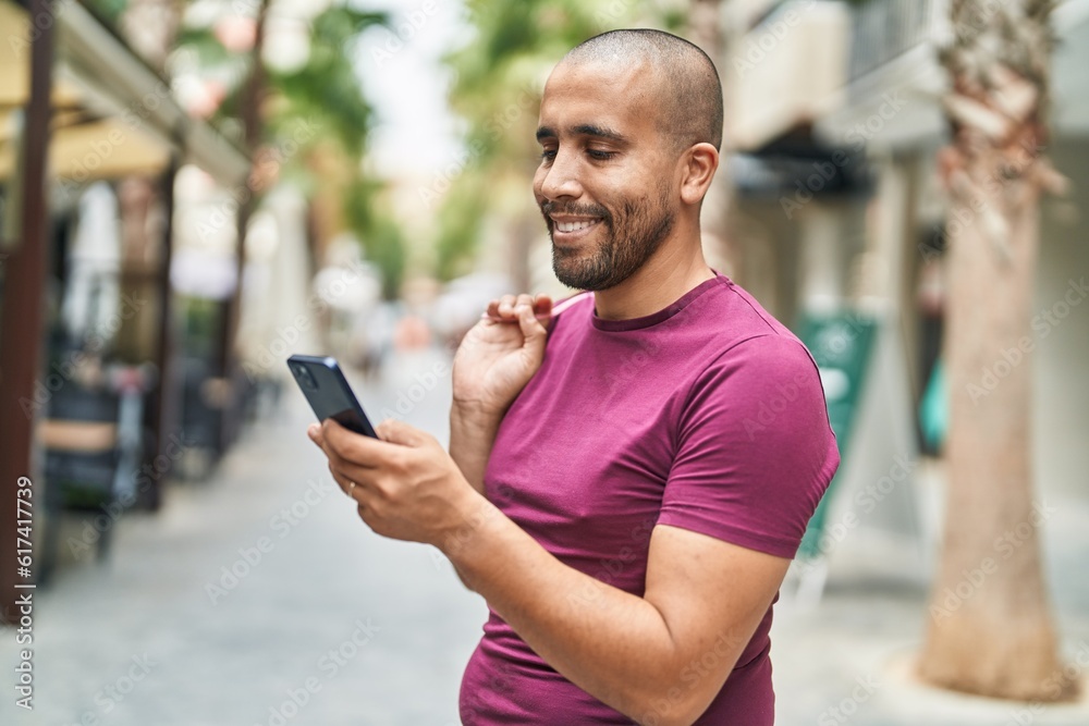 Young latin man using smartphone holding shopping bag at street Young latin man using smartphone holding shopping bag at street
