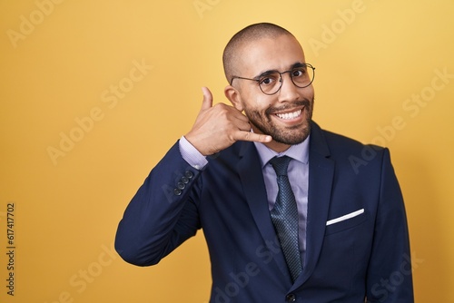 Hispanic man with beard wearing suit and tie smiling doing phone gesture with hand and fingers like talking on the telephone. communicating concepts. © Krakenimages.com