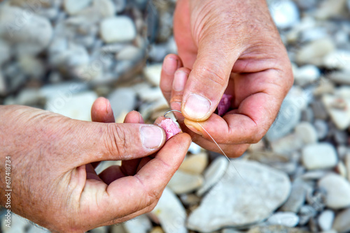 Bilde på lerret Man's hands close-up with fishing rod hook puts bacon bait on the beach