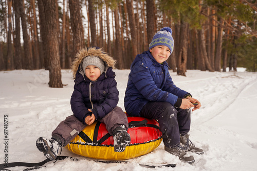 Children sit on tubing in the snowy forest and take a break from the winter fun. Happy children in winter.