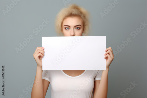 young woman holding blank white paper size banner sign, closeup isolated studio portrait