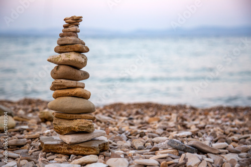 Pebbles tower balances harmony stones on the Aegean sea coast at sunset. Relaxing spa tranquility concept 