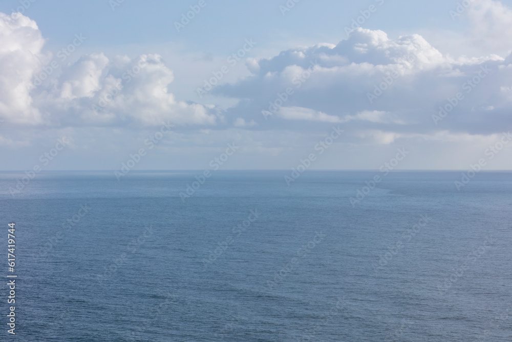 White clouds in a blue sky over the Pacific ocean at dusk White clouds in a blue sky over the Pacific ocean at dusk