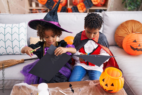 Adorable african american boy and girl having halloween party cutting paper at home