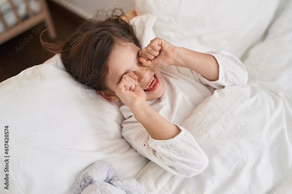 Adorable hispanic girl lying on bed waking up at bedroom Adorable hispanic girl lying on bed waking up at bedroom