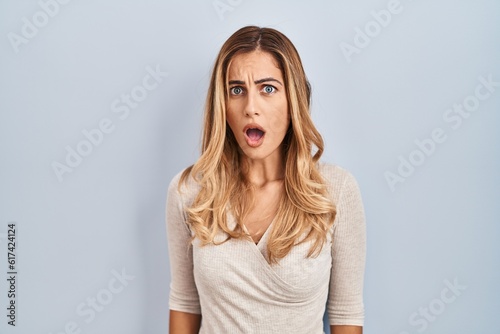 Young blonde woman standing over isolated background afraid and shocked with surprise and amazed expression, fear and excited face.