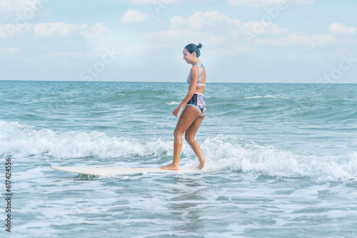 Asian women wearing swimsuits hobby happy fun surfing waves on board in the sea is an exciting water sport on the beach in Thailand