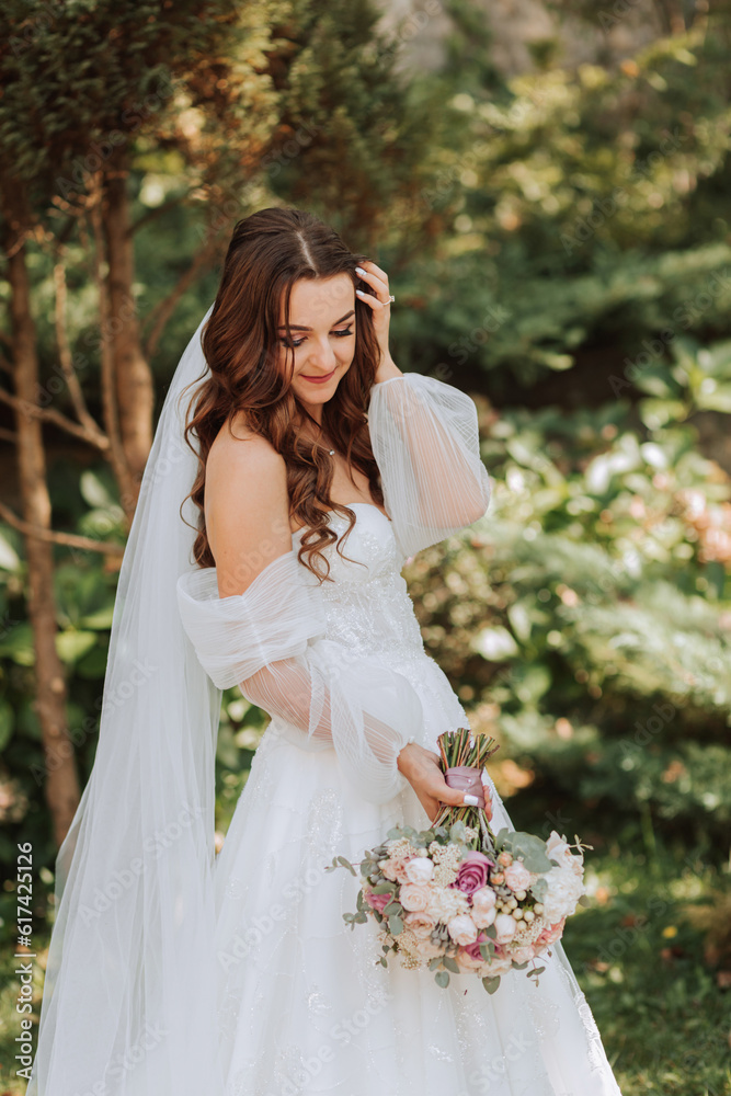 young and beautiful bride with long brown hair in a wedding dress outdoors with a wedding bouquet of flowers. Portrait of a girl in a white dress young and beautiful bride with long brown hair in a wedding dress outdoors with a wedding bouquet of flowers. Portrait of a girl in a white dress