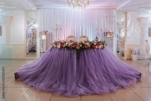 the bride's table is decorated in the restaurant in purple color, preparation for the wedding celebration. photo