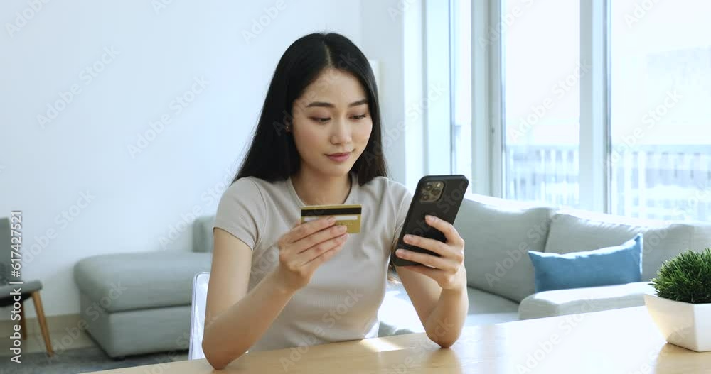 Attractive Asian woman holding credit card do e-shopping using cellphone, make payment use secure e-bank application, transfers money through mobile app, ordering, buying goods via e-commerce website Attractive Asian woman holding credit card do e-shopping using cellphone, make payment use secure e-bank application, transfers money through mobile app, ordering, buying goods via e-commerce website