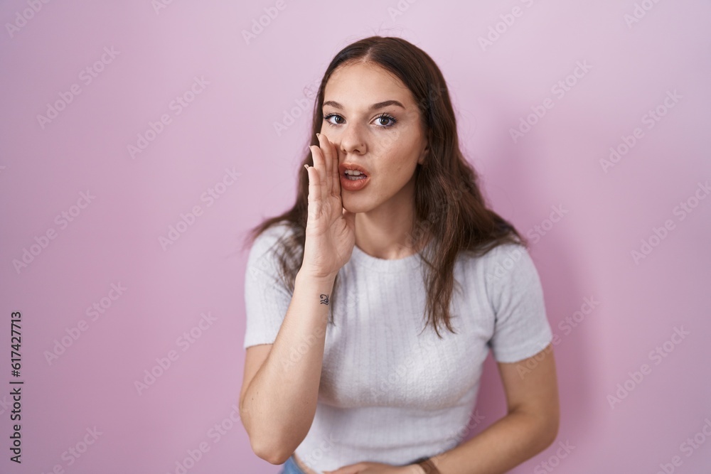 Young hispanic girl standing over pink background hand on mouth telling secret rumor, whispering malicious talk conversation Young hispanic girl standing over pink background hand on mouth telling secret rumor, whispering malicious talk conversation