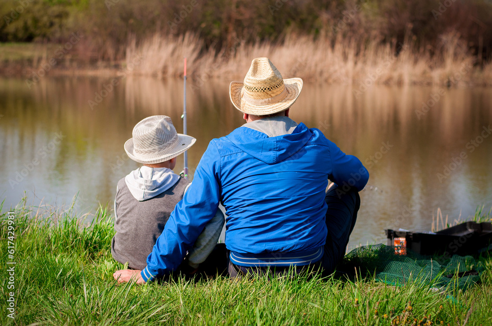 Dad and son fishing on the lake in the summer Dad and son fishing on the lake in the summer