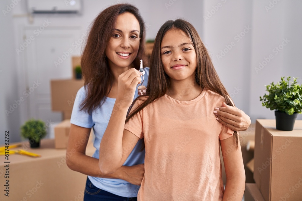 Woman and girl mother and daughter holding key at new home Woman and girl mother and daughter holding key at new home